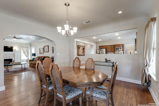 2106 W Gramercy Pl, San Antonio, TX 78201 - dining space featuring wood finished floors, visible vents, arched walkways, ceiling fan with notable chandelier, and a wealth of natural light