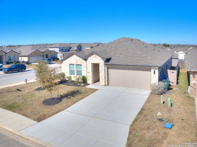 view of front of property with driveway, roof with shingles, an attached garage, stone siding, and a residential view