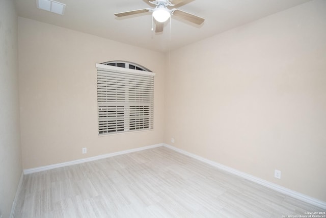 empty room with wood finished floors, a ceiling fan, baseboards, and visible vents