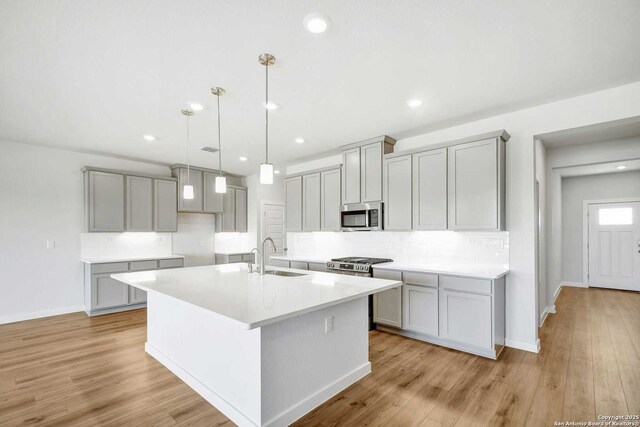 1514 Saddleback, New Braunfels, TX 78130 - kitchen with a sink, a kitchen island with sink, stainless steel microwave, baseboards, and gray cabinetry