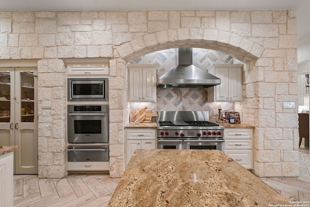 1626 Cordillera Trce, Boerne, TX 78006 - kitchen with stainless steel appliances, wall chimney range hood, a warming drawer, light stone countertops, and tasteful backsplash