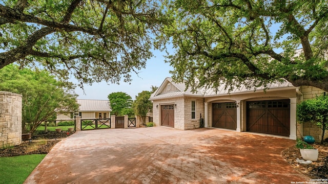 1626 Cordillera Trce, Boerne, TX 78006 - view of front facade with a gate, concrete driveway, stone siding, fence, and metal roof