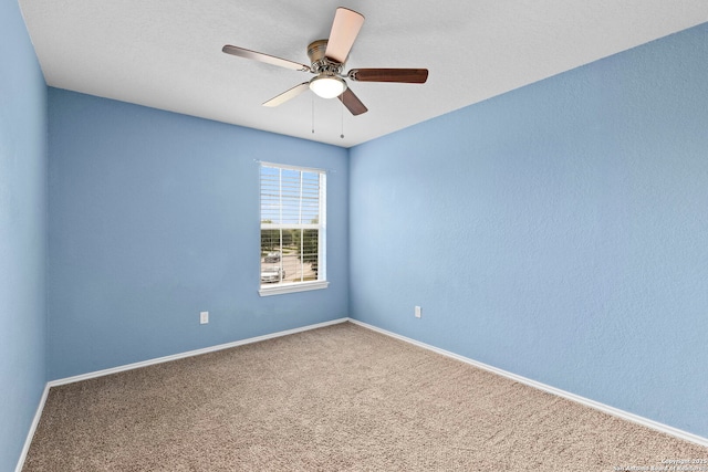 carpeted spare room featuring ceiling fan and baseboards