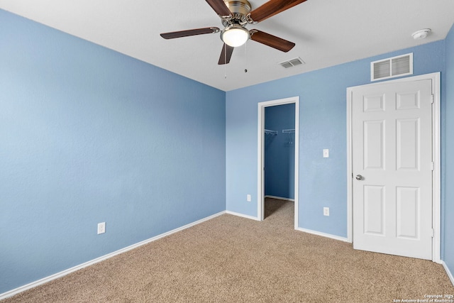 unfurnished bedroom featuring visible vents, a spacious closet, carpet, and baseboards