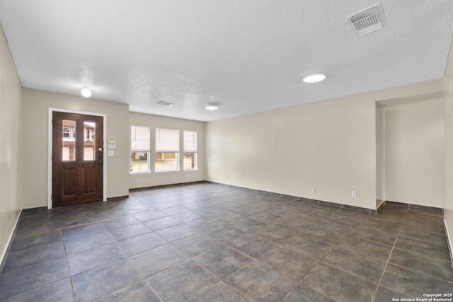 entrance foyer with dark tile patterned flooring, baseboards, a textured ceiling, and visible vents