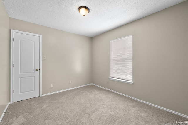 spare room featuring baseboards, carpet, and a textured ceiling