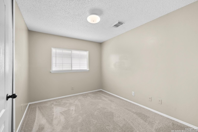 unfurnished room with baseboards, carpet flooring, a textured ceiling, and visible vents