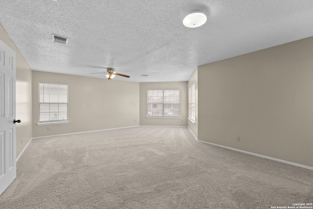 carpeted spare room with baseboards, a textured ceiling, visible vents, and ceiling fan