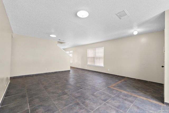spare room with tile patterned floors, baseboards, a textured ceiling, and visible vents