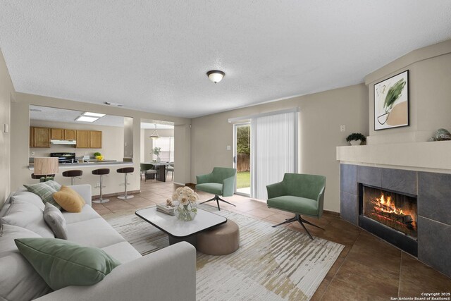 living area featuring a textured ceiling, light tile patterned floors, and a tile fireplace