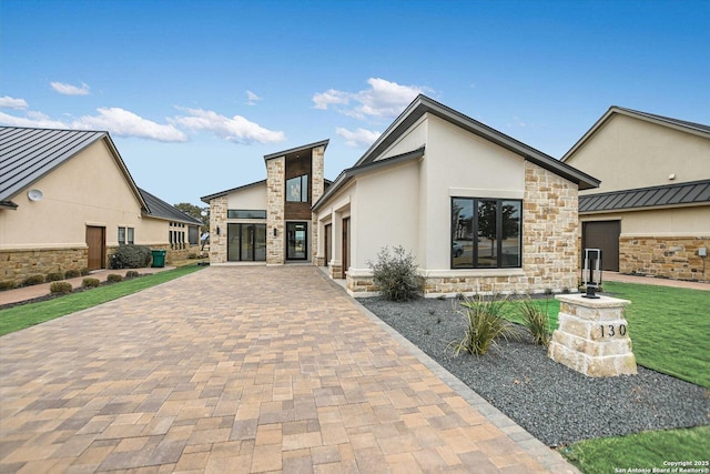 exterior space with stone siding, stucco siding, decorative driveway, and a garage