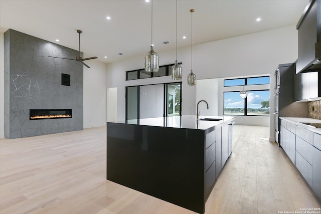130 Azalea Loop, Horseshoe Bay, TX 78657 - kitchen with wall chimney range hood, light wood-style floors, a large island, modern cabinets, and a sink