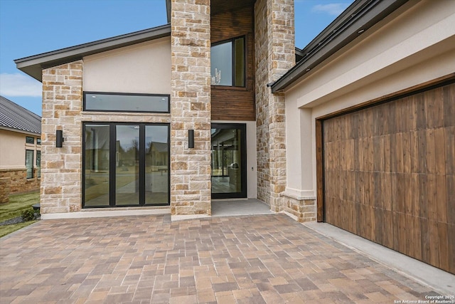 view of exterior entry with stone siding and stucco siding