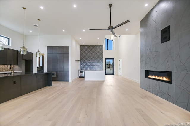 130 Azalea Loop, Horseshoe Bay, TX 78657 - living area featuring a ceiling fan, recessed lighting, a fireplace, light wood-style floors, and a towering ceiling
