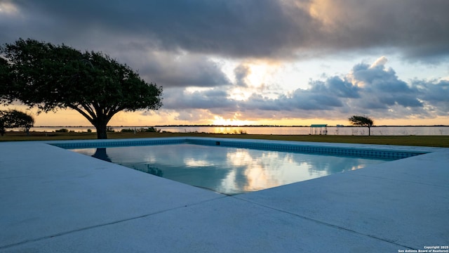 pool at dusk featuring a patio and an outdoor pool