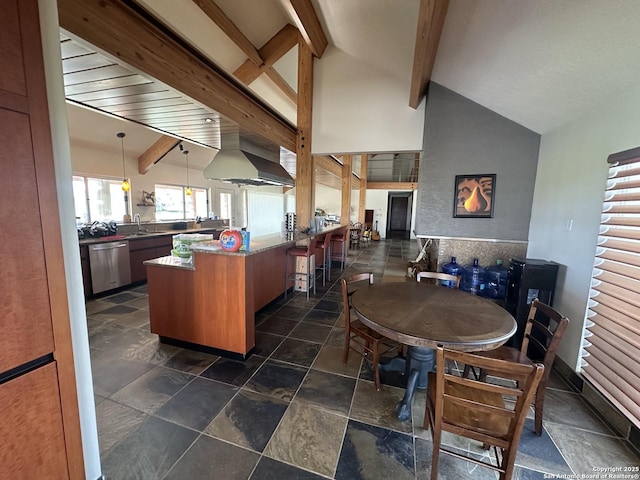 kitchen featuring a kitchen bar, a peninsula, wall chimney exhaust hood, dishwasher, and vaulted ceiling with beams