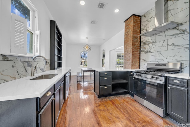 kitchen featuring visible vents, a sink, open shelves, appliances with stainless steel finishes, and wall chimney exhaust hood