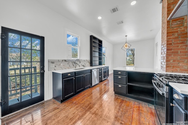 kitchen with open shelves, appliances with stainless steel finishes, dark cabinetry, and light countertops