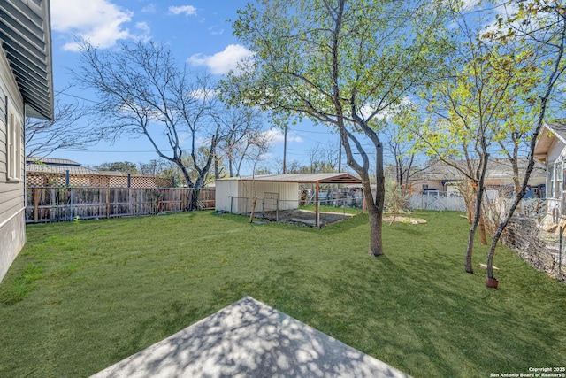 view of yard with a detached carport, an outbuilding, and a fenced backyard