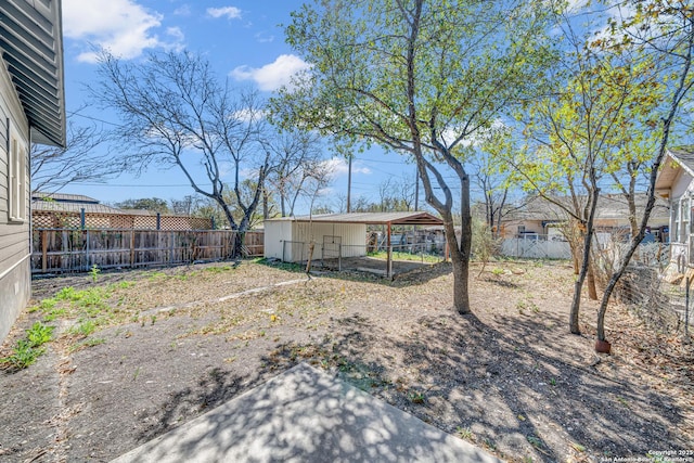 view of yard with a detached carport, an outdoor structure, and a fenced backyard