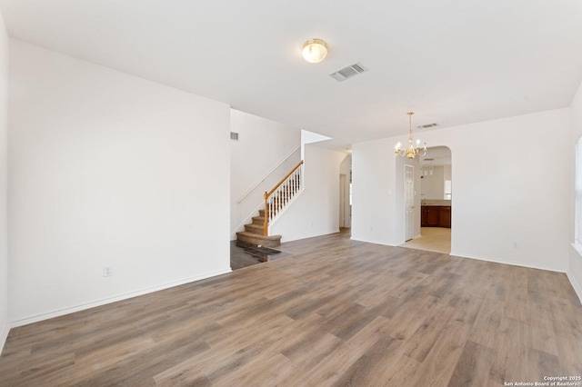 12319 Stable Road Dr, San Antonio, TX 78249 - unfurnished living room with visible vents, a notable chandelier, light wood-style flooring, stairway, and arched walkways