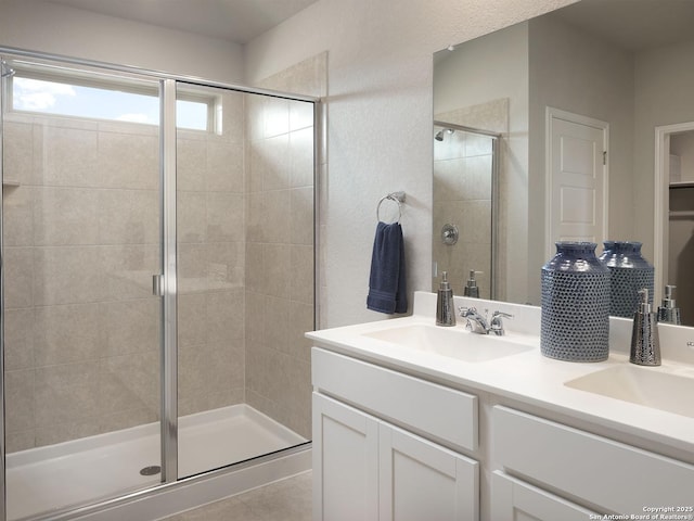 full bath featuring double vanity, a stall shower, and a sink