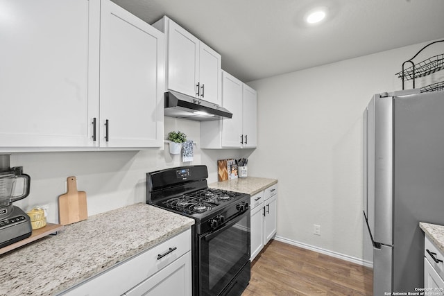 923 Empress Brilliant, San Antonio, TX 78253 - kitchen featuring under cabinet range hood, black gas range, light wood-style flooring, freestanding refrigerator, and white cabinetry