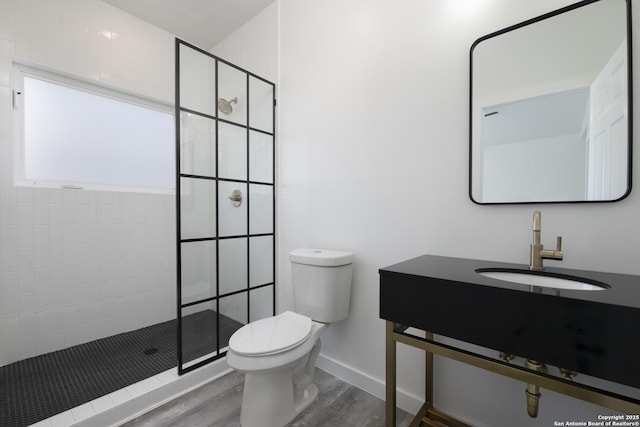 106 Bank St Unit 201, San Antonio, TX 78204 - full bath with vanity, wood finished floors, baseboards, a tile shower, and toilet