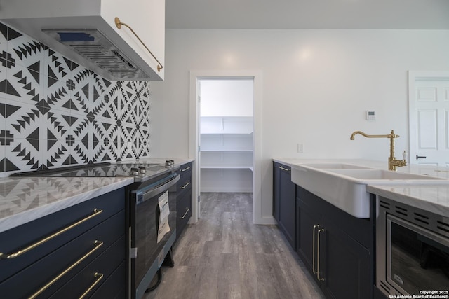 106 Bank St Unit 201, San Antonio, TX 78204 - kitchen featuring extractor fan, light stone countertops, stainless steel range with electric cooktop, wood finished floors, and a sink
