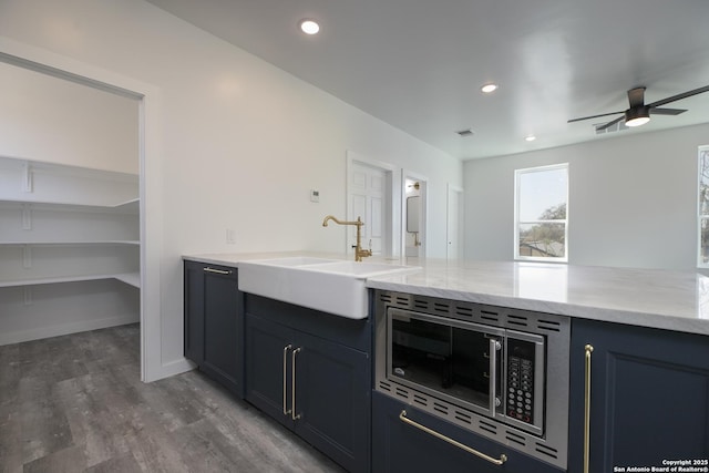 106 Bank St Unit 201, San Antonio, TX 78204 - kitchen with light stone counters, wood finished floors, ceiling fan, a sink, and stainless steel microwave