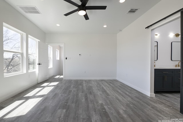 106 Bank St Unit 201, San Antonio, TX 78204 - unfurnished living room with visible vents, a ceiling fan, a barn door, and wood finished floors