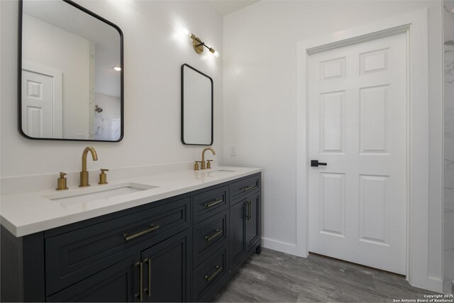 106 Bank St Unit 201, San Antonio, TX 78204 - bathroom featuring double vanity, wood finished floors, baseboards, and a sink
