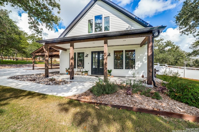 view of front facade with french doors, a porch, a front lawn, and fence