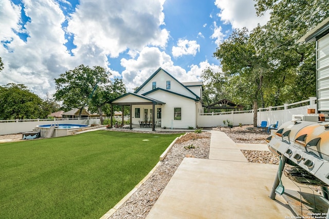 rear view of property with a fenced in pool, a lawn, a fenced backyard, and a patio area