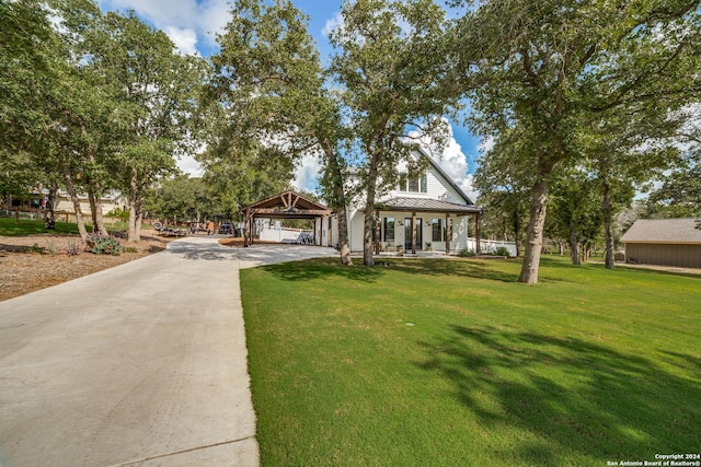 view of front of home featuring driveway, a front lawn, a standing seam roof, metal roof, and a carport
