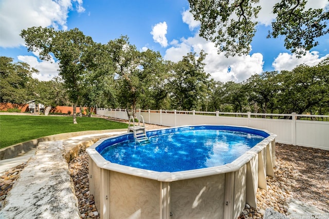 view of pool with a lawn and a fenced backyard