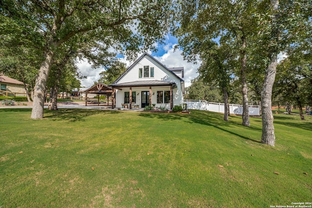rear view of property with a gazebo, metal roof, a lawn, and fence