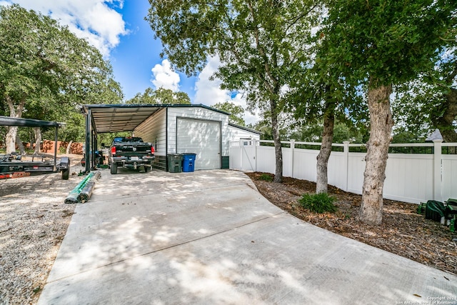 garage featuring driveway, a detached garage, and fence