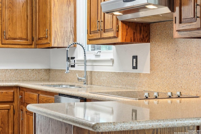 kitchen with under cabinet range hood, a sink, stainless steel dishwasher, brown cabinetry, and black electric cooktop