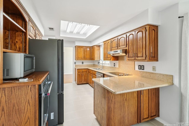 kitchen with white microwave, visible vents, a peninsula, a sink, and under cabinet range hood