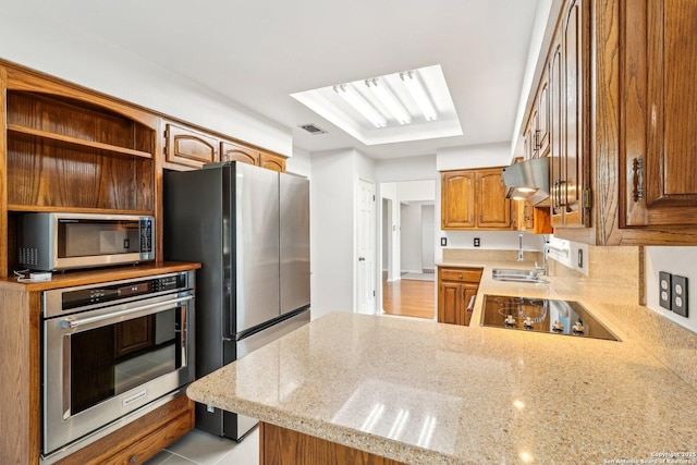 kitchen with a sink, under cabinet range hood, appliances with stainless steel finishes, a peninsula, and open shelves