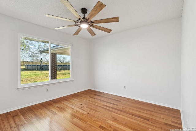 empty room featuring ceiling fan, baseboards, and light wood-style floors
