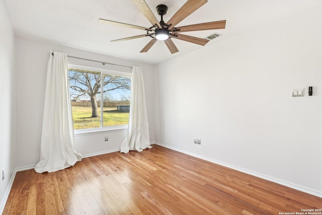 spare room featuring baseboards, visible vents, light wood finished floors, and ceiling fan