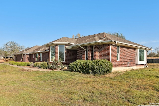 view of side of property with brick siding and a yard