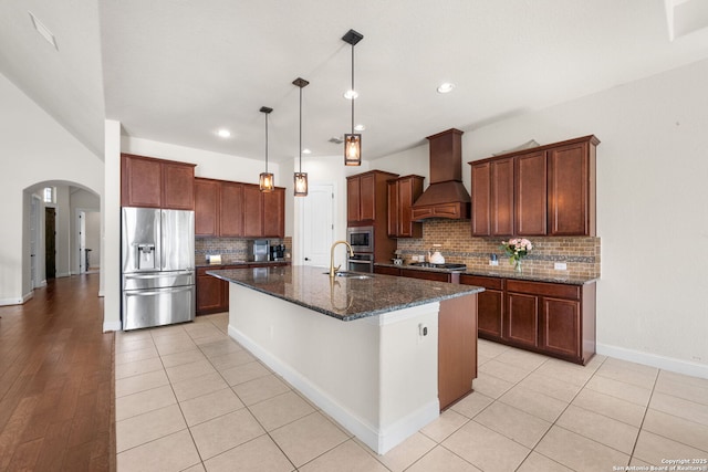 13606 Beck Ml, San Antonio, TX 78253 - kitchen with a kitchen island with sink, dark stone countertops, arched walkways, appliances with stainless steel finishes, and custom exhaust hood
