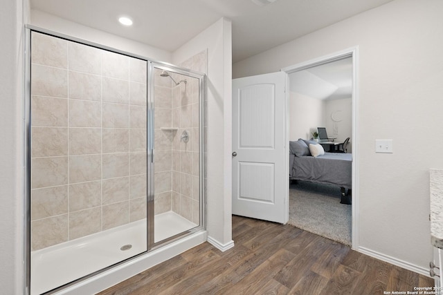 full bathroom featuring a stall shower, ensuite bath, baseboards, and wood finished floors