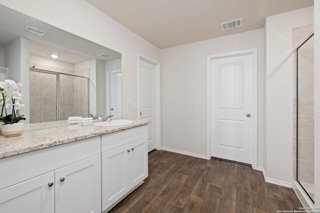 full bath with visible vents, baseboards, a stall shower, wood finished floors, and vanity
