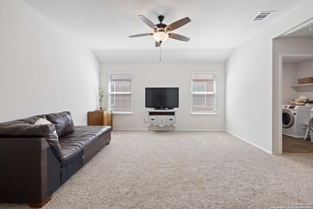living area with baseboards, washer / dryer, lofted ceiling, ceiling fan, and light colored carpet