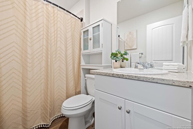 bathroom with toilet, wood finished floors, and vanity
