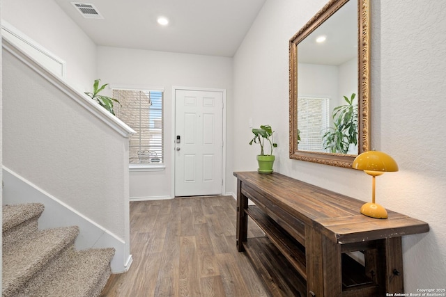 entrance foyer with visible vents, baseboards, stairs, recessed lighting, and wood finished floors